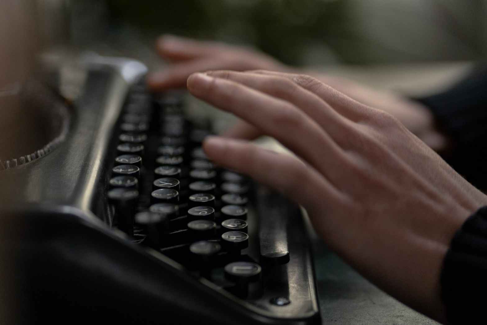 Close-up of a pair of hands typing on a typewriter.